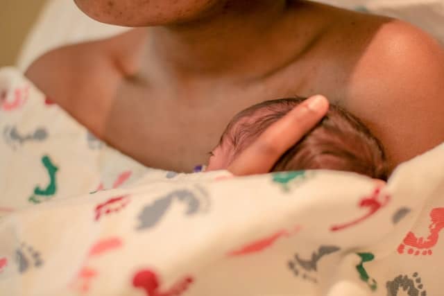 mom holding her new born about her arms - a drug free childbirth