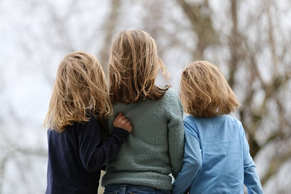 siblings - three sisters holding one another 12px