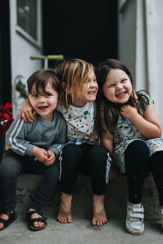 three children sitting together and smiling