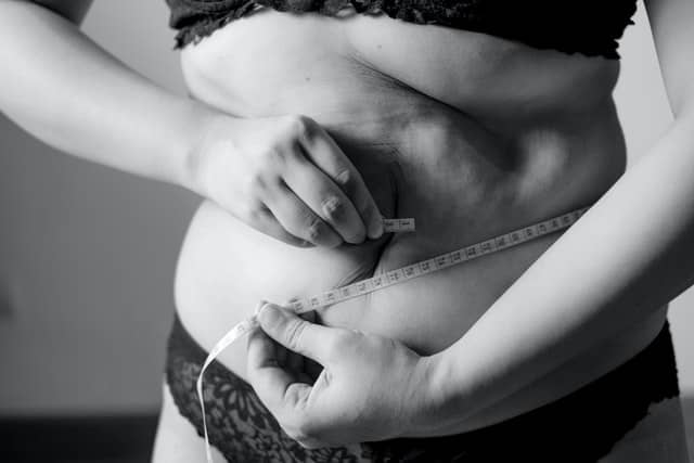 woman holding a tape around her belly - losing weight
