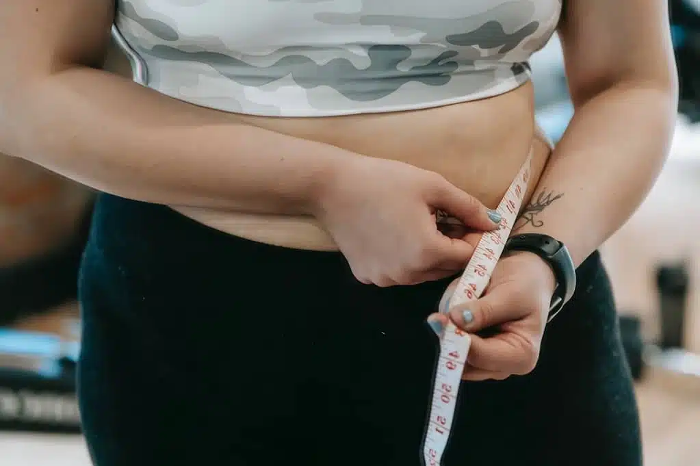 woman holding a tape around her belly
