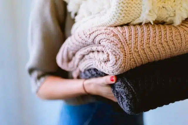 declutter and laundry - woman holding pile of wrapped clothes