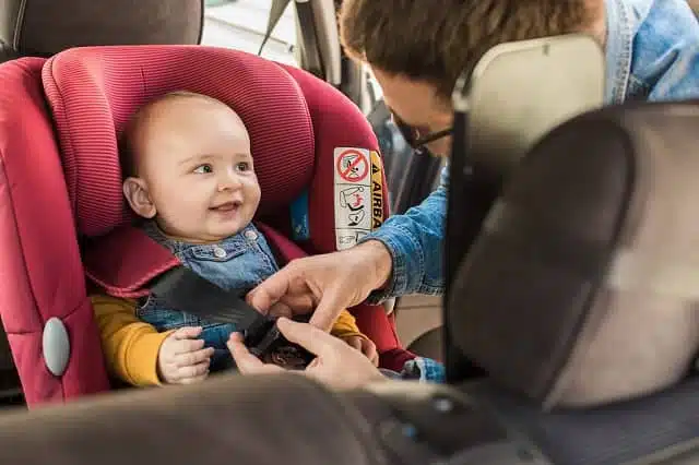 father fastening his baby in a convertible car safety seat