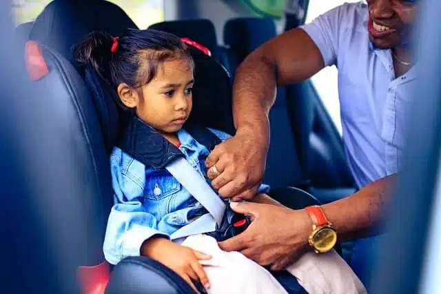 father installing his daughter safety seat