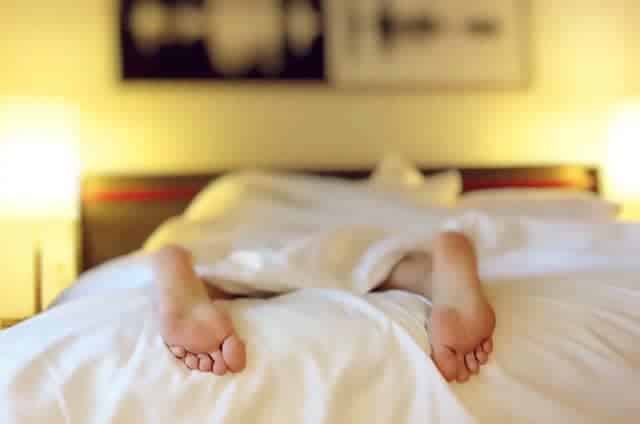 mom resting on bed with white bedspread