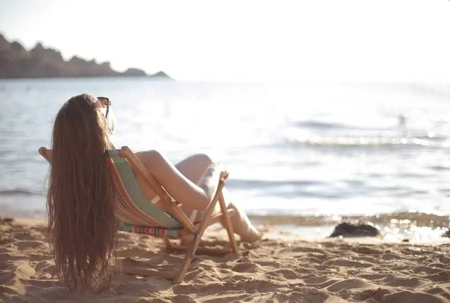tanning while pregnant: woman sitting at the beach tanning