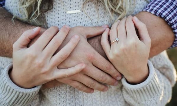 woman cuddling husband hand